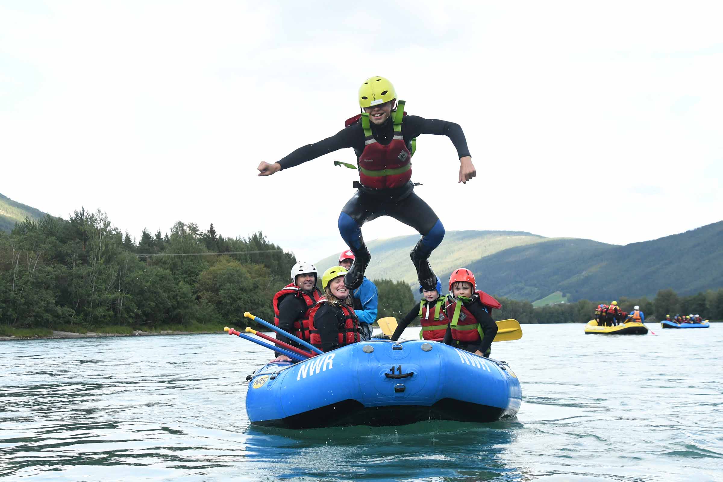 Gutt som hopper fra fronten på raftingbåten og ut i vannet